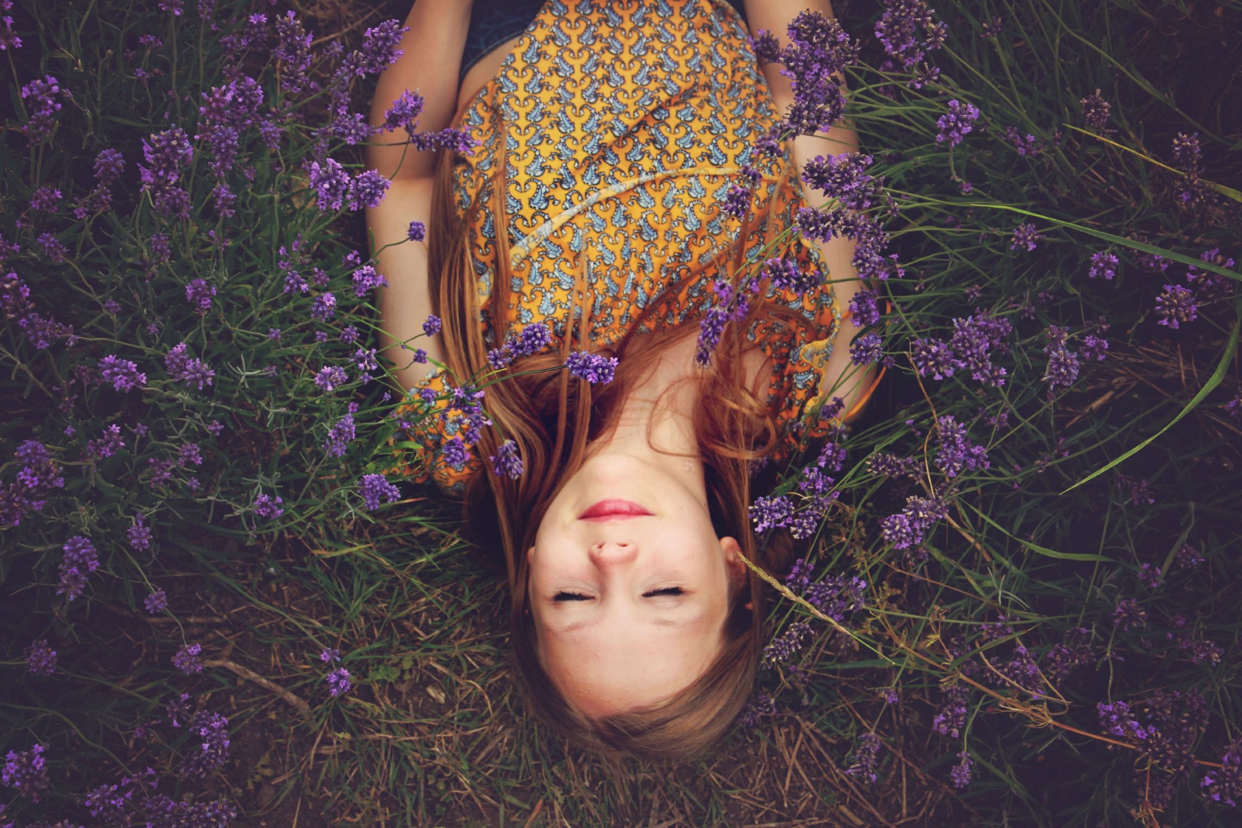 Woman lying on her back among lavender with her eyes closed